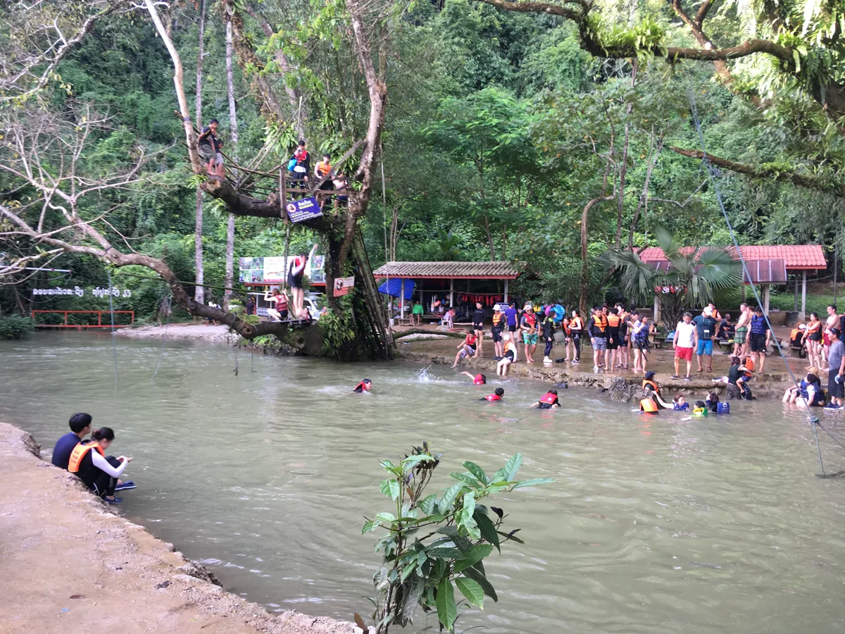 Turquoise natural spring water of Blue Lagoon surrounded by towering trees in Vang Vieng