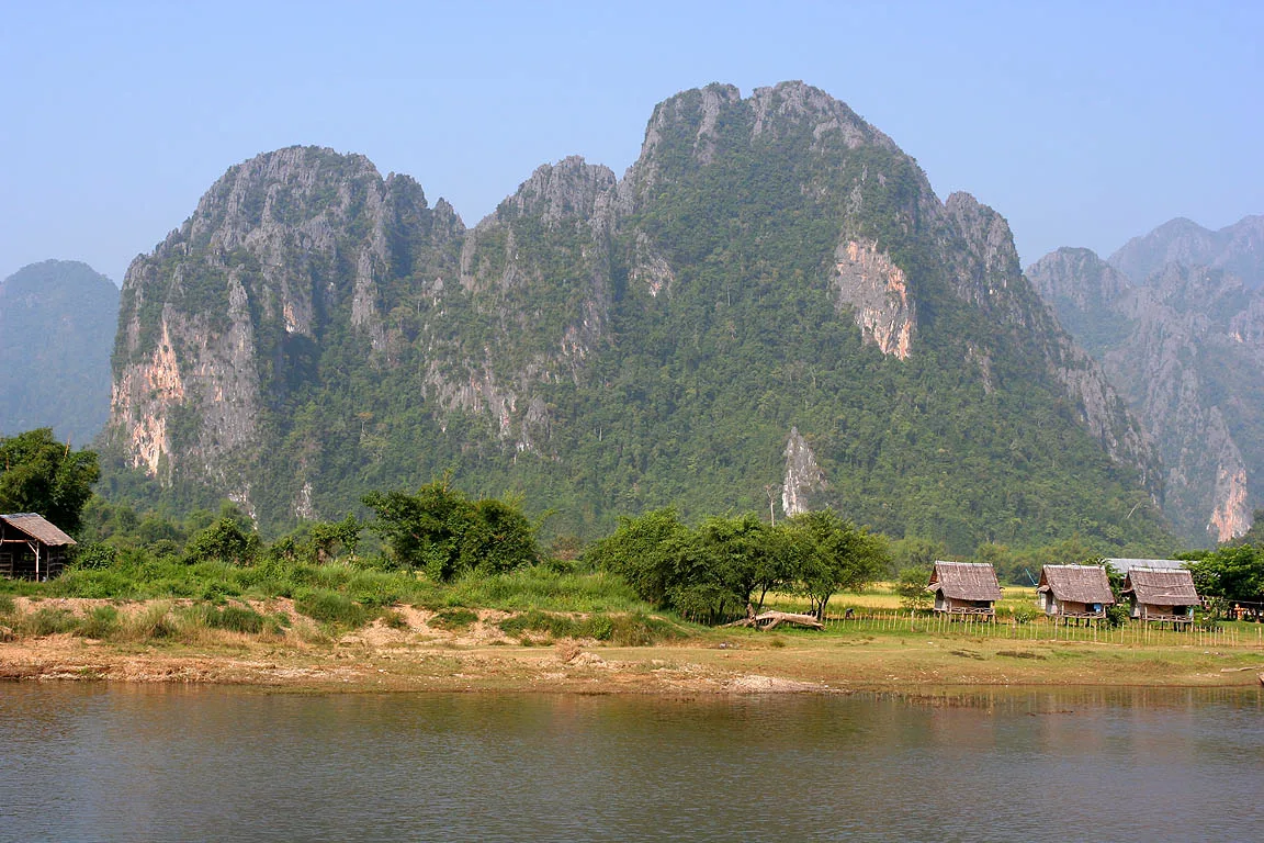 Longtail boats and serene waters on the Nam Song River against limestone cliffs in Vang Vieng
